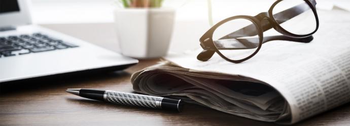 stylised image of a pair of glasses sitting on top of a folded newspaper