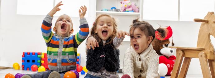 Three early years children playing with plastic balls 