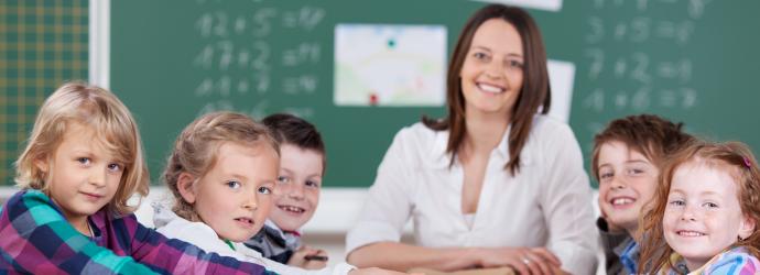 A stock image of children in a classroom with their teacher