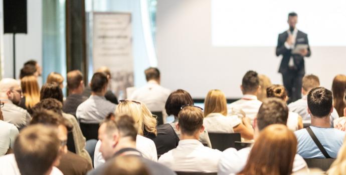 Group of people listening to man on stage