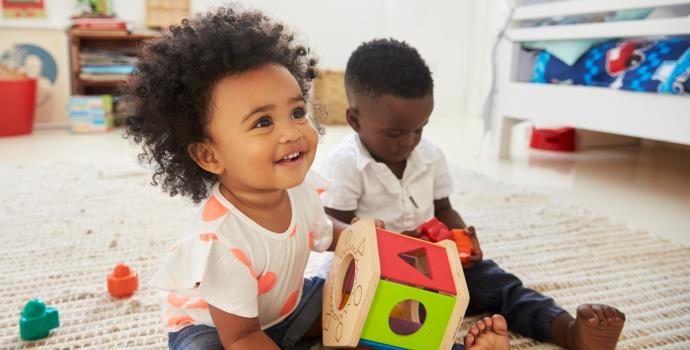 two children playing on with a toy on the floor