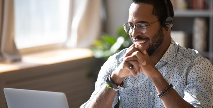 man smiling as he looks at laptop screen