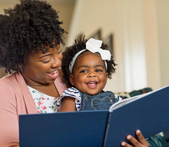 A mother and her toddler daughter reading a book together