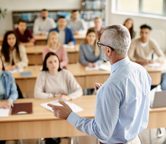 A male teacher giving a lecture to FE students who are all sitting at desks