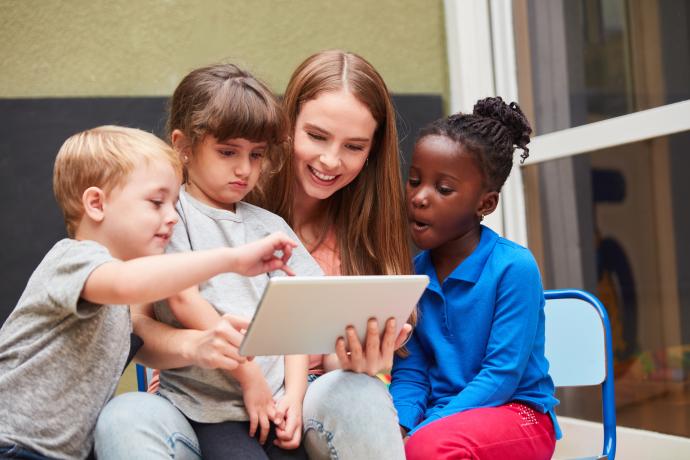 Teacher and children have fun learning with a tablet computer in the day care centre