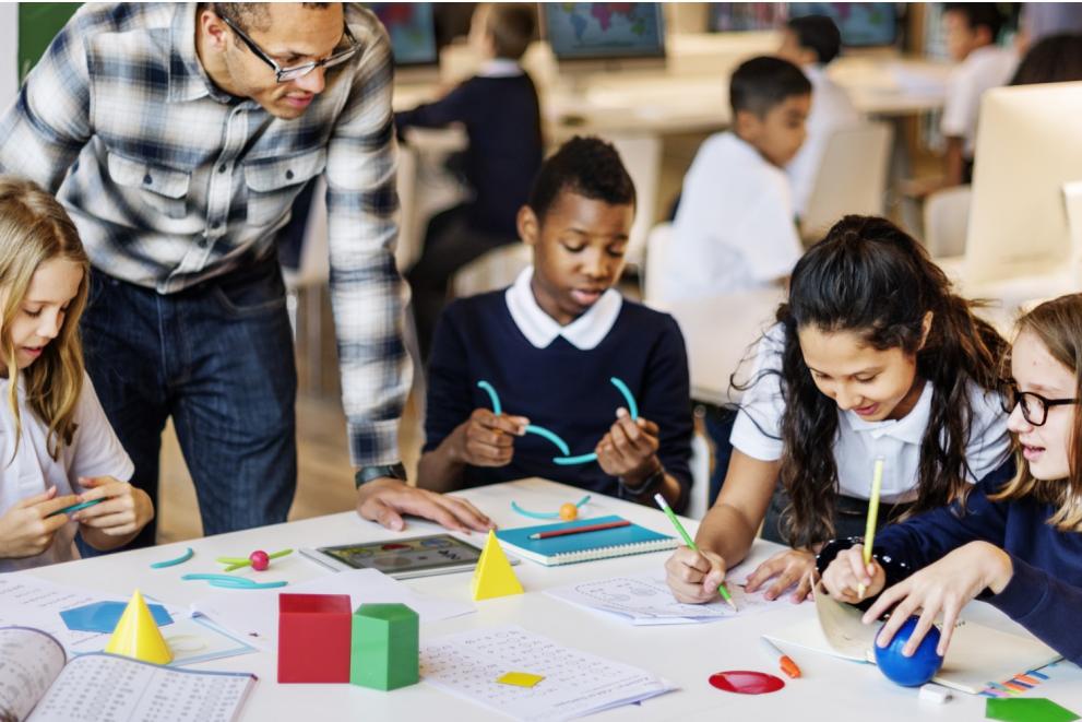 male teacher with children around table in class