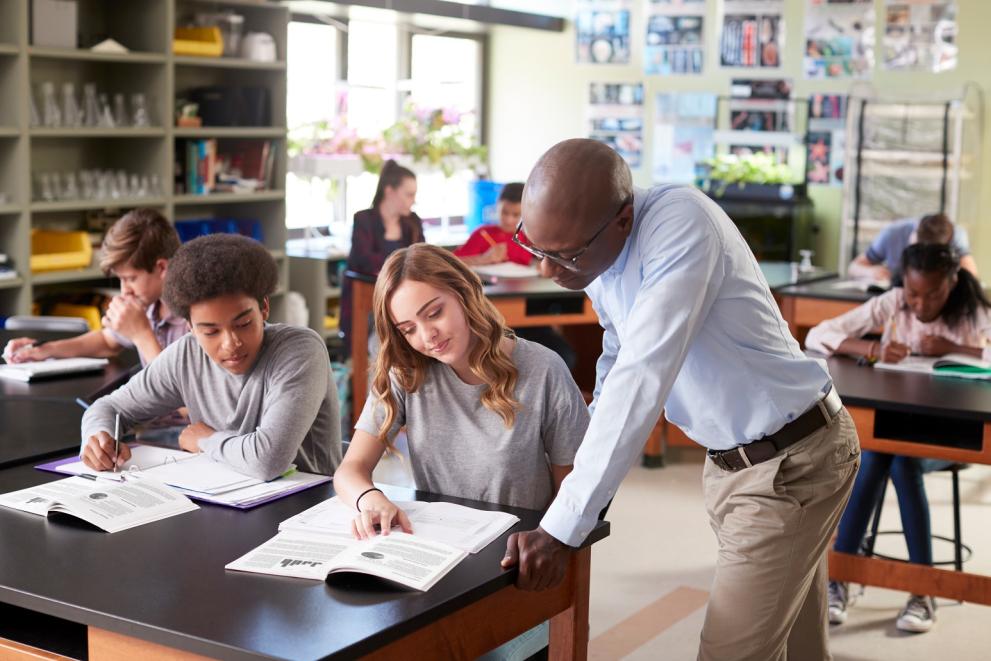 young people in a science classroom with male teacher